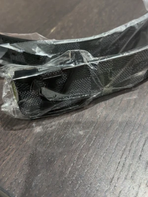 Svart Louis Vuitton bälte med LV-spänne - Snyggt svart bälte från Louis Vuitton med klassiskt LV-spänne i metall. Bältet har en diskret mönstrad yta och är tillverkat i ett tåligt material. Perfekt accessoar för att lyfta din outfit.