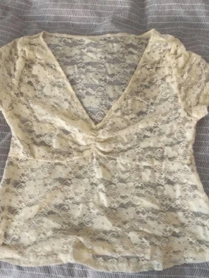 Beige spetsblus med v-ringning - Säljer en beige, kortärmad spetsblus.