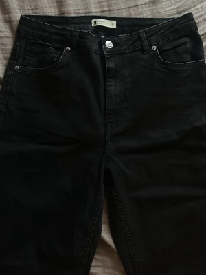 Svarta bootcut jeans med hög midja - Snygga svarta jeans med bootcut passform och hög midja. Klassisk femficksmodell med knapp och dragkedja framtill. Tillverkade i ett mjukt jeansmaterial som sitter bekvämt och ger en clean look. Skit stretchiga + knappt använda.