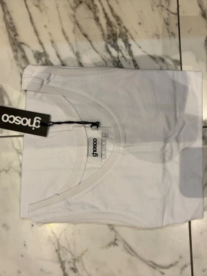 Vit linnetopp  - Säljer en klassisk vit linnetopp från Ginosco. Toppen är ärmlös med rund halsringning och tillverkad i mjuk bomull, perfekt för en enkel och stilren look. Passar till allt och är ett måste i garderoben. Den säljs i storleken S/M/L. Så skriv vilken storlek du vill ha så löser jag.