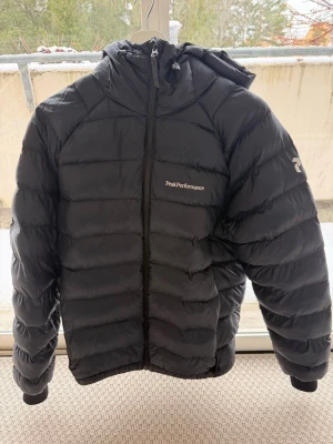Svart dunjacka Peak Performance - Svart vinterjacka från Peak Performance med luva. Använd förra vintern. Håller värmen bra och skön att ha på sig. Finns en liten skada i högerfickan pga dragkedjan fastnade. Säljer nu pga köp av ny jacka. Köpt för ca 2500, säljer för 950.