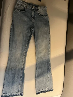 Zara jeans flared Size 38  - Ljusblå jeans med rak passform och rå, fransad kant nertill. Klassisk femficksmodell med hög midja och dragkedja. Perfekta för en avslappnad och trendig look.
