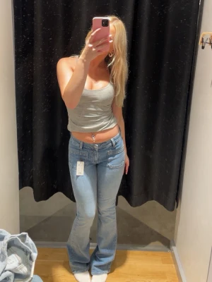 Ljusblå bootcut jeans med fickor - Säljer ett par ljusblå jeans med bootcut passform och stora framfickor. Jeansen har låg midja och klassisk femficksdesign. Tillverkade i mjukt denimtyg som ger en skön känsla och snygg siluett. Perfekta för dig som gillar en avslappnad men trendig look.