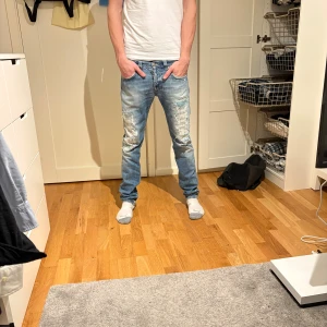 Dondup 32 - Snygga ljusblå dondup Waits 32 jeans med slitna detaljer och klassisk femficksdesign. Jeansen har normal passform och är tillverkade i bomull med en touch av stretch för extra komfort. Perfekta för en avslappnad och trendig look.