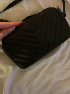 Svart quiltad axelväska  - Snygg svart axelväska med justerbar axelrem. Har haft den länge men den är använd 1-2 gånger bara max! Kommer inte riktigt ihåg vart den är från men tror HM💓