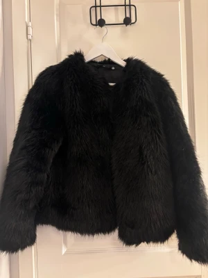 Svart pälsjacka  - Snygg svart pälsjacka i fuskpäls, Jackan har lång ärm och är perfekt för festliga tillfällen! Den är i väldig bra skick, inget slitage. PS! Jag skickar posten om du köper innan kl 17🥰
