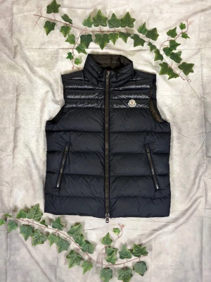 Moncler Dupres Down Vest – Mörkblå – Strl 3 (M) - |Färg: Mörkblå/navy, matt/blank mix | Modell: Dupres Down Vest, lättviktsdun | Storlek: 3 (M), normal passform | Skick: Grade B, 8,5/10 (tvättbara fläckar) | Hör av dig ifall du har funderingar!
