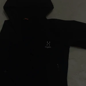 Svart haglöfs-jacka - Säljer en Haglöfs-jacka i storlek S. Jackan är i fint skick utan några skador eller konstigheter. Den har både fickor och luva. Köpt för 1299 kr men säljs nu för 450 kr då den är för liten och inte riktigt min stil längre.