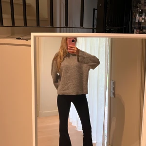 Grå stickad tröja med loose fit - Mysig grå stickad tröja med avslappnad, loose passform och långa ärmar. Tröjan har en enkel design med ribbade muddar vid ärmslut och nederkant. Perfekt för lager-på-lager och chill dagar.