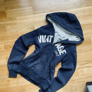Vintage Y2K zip up med pälsfoder - Supermysig marinblå hoodie med dragkedja och fodrad insida som håller dig varm och bekväm. Trycket ”Vintage 1962” framtill ger en retro känsla och gör den både snygg och tidlös. 	•	Storlek: S 	•	Färg: Marinblå 	•	Bra skick, sparsamt använd 	•	Rare modell – svår att hitta  Perfekt för hösten 🍂 – funkar lika bra till jeans som till mjukisbyxor för en avslappnad men stilren look.