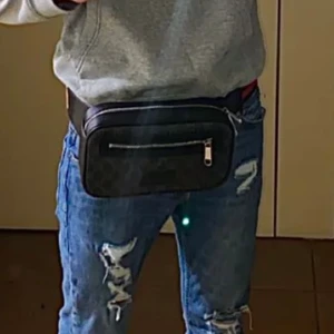 Gucci svart axelväska med GG-mönster - Snygg svart axelväska från Gucci med klassiskt GG- mönster i grått. Väskan har silverfärgad dragkedja framtill, detaljer i skinn och justerbar axelrem i rött och marinblått. Perfekt storlek för det viktigaste och en riktigt stilren accessoar