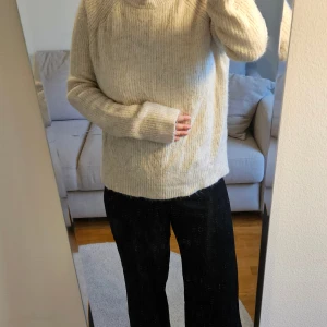 Stickad tröja - Mysig beige/cremefärgad stickad tröja från H&M. Tröjan har ribbade muddar, lång ärm och en hög krage som ger extra värme. Enkel och stilren design som funkar till allt. Mjukt och mysigt material!