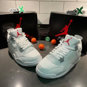 Air Jordan 4 Retro White Oreo - Nike Air Jordan 4 i helvitt skinn med röda detaljer och Jumpman-logga på plös och sula. Skorna har meshpaneler, gråa detaljer med stänk och klassisk snörning. Perfekt för dig som vill sticka ut med en ikonisk sneaker.