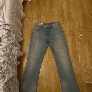 Ljusblå bootcut jeans från Zara - Säljer ett par ljusblå jeans från Zara i storlek 38. Jeansen har bootcut-modell med råa, avklippta benslut och klassisk femficksdesign. Tillverkade i bomull med en snygg tvättad look. Perfekta för dig som gillar en avslappnad men trendig stil. Aldrig använda