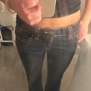 Mörkblå jeans från Gina Tricot - Snygga mörkblå jeans från Gina Tricot med kontrasterande vita sömmar och orange detaljer. Modellen är lågmidjad och har klassisk femficksdesign. Jeansen är i stretchigt denimtyg och passar perfekt till en trendig vardagslook.