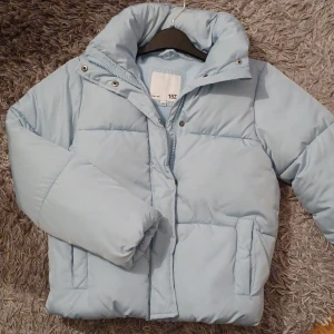 Ljusblå pufferjacka från 157 - Säljer en ljusblå pufferjacka från lager 157 med hög krage och dragkedja framtill 💙 Stl 140