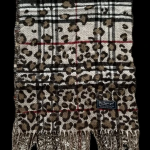 Burberrys leopardrutig ullhalsduk - Snygg halsduk från Burberrys i 100% lammull med både rutigt och leopardmönster. Färgerna går i beige, brunt, svart och vitt med röda detaljer. Klassisk fransad kant och cool mix av mönster som sticker ut.