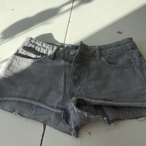 Grå jeansshorts från 157 Lexi - Snygga grå jeansshorts från 157, modell Lexi. De har råa, fransiga kanter och klassisk femficksdesign. Perfekta för en avslappnad stil med en cool edge. Passar dig som gillar en enkel men trendig look.