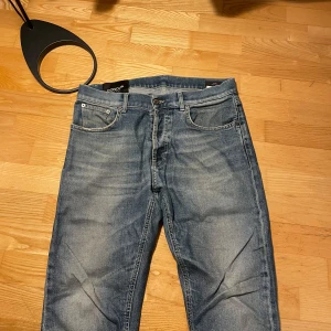 Blå jeans från Dondup - Säljer ett par blå jeans från Dondup i modellen Dian Carrot Slim Fit. Jeansen har klassisk femficksdesign, snygga slitningar och orange sömmar. De är tillverkade i bomull och har en något avsmalnande passform med normal midja.