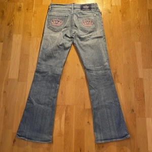 Victoria Beckham Bootcut Jeans - Ljusblåa Bootcut Jeans från Victoria Beckham i storlek 27 med rosa kronor på bakfickorna! Skriv gärna för mer info eller bilder på detaljer :)