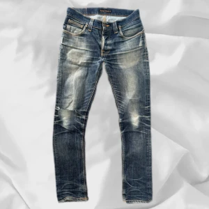 Nudie Grim Tim - Stört snygga Nudie Jeans i modellen Grim Tim, strlk 31/32 med en fet wash och snygg slitning på knät – enkla att matcha och sköna att bära. Ett stilrent val, noggrant utvalt med omsorg av AM Clothing.  📩 Frågor? Hör gärna av dig! 📲 Följ oss här på Plick för fler uppdateringar. ♻️ Tack för att du handlar mer hållbart med AM Clothing!