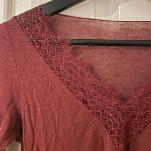 Vinröd långärmad topp med spets från intimissimi - Supersnygg vinröd långärmad topp från Intimissimi med v-ringning och dekorativ spets runt halsringningen och vid ärmsluten. Tunn och mjuk i materialet, super fin till hösten💕