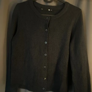 Svart stickad kofta från 157 - Mysig mörkblå stickad kofta från 157 med rund halsringning och knappar framtill. Perfekt att slänga över ett linne eller t- shirt. Långärmad och enkel design som funkar till det mesta. Jätte fin stickad kofta och perfekt till hösten. Säljs för att den inte kommer till användning. Kontakta för egna bilder. 