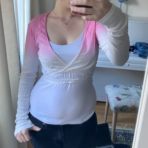Bolero i rosa och vitt - Supersöt omlottopp med långa ärmar i en snygg gradient från rosa till vitt. Tunn och stretchig, med knytband i midjan som ger en smickrande passform. Perfekt till jeans eller kjol för en fräsch look.