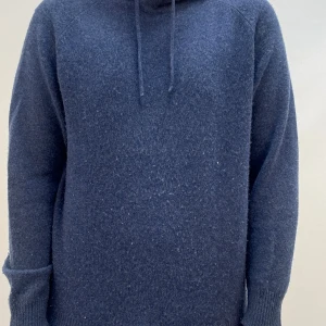 Soft goat Blå stickad hoodie med snörning - Mysig mörkblå stickad hoodie med snörning i halsen och långa ärmar. Tröjan har en avslappnad passform och ribbade muddar vid ärmslut och nederkant. Perfekt för kyliga dagar när du vill vara både bekväm och snygg.