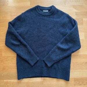 Mörkblå stickad tröja från Zara - Mysig mörkblå stickad tröja från Zara med rund halsringning och ribbade muddar. Perfekt för kyliga dagar och enkel att matcha med jeans. Klassisk modell med lång ärm och mjukt material.