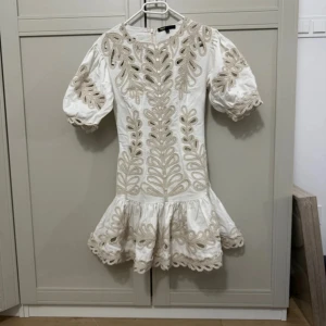 Vit kortklänning med broderi från Maje - Superfin vit kortklänning från Maje med puffärmar och beige broderade detaljer. Aldrig använd då den tyvärr är för liten för mig som bär S❣️ganska liten i storleken 
