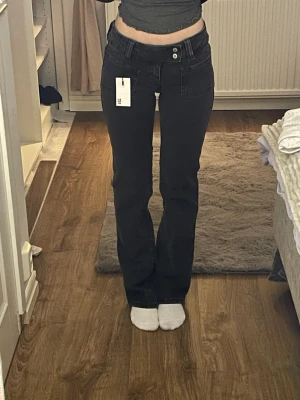 Svarta bootcut jeans - Säljer ett par svarta bootcut jeans från 157 i storlek XXS short. De har inte blivit använda, utan tog på dem för att sälja. Jeansen har låg midja och raka ben som går ut lite nertill. Materialet är stretchigt jeans och färgen är mörk svart.