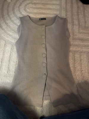 Beige stickad väst från Zara - Säljer en beige stickad väst från Zara i storlek S. Västen har rund halsringning, stora tygklädda knappar framtill.  knappt är använd. 🤎