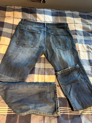 Lee jeans - Säljer ett par blå jeans med bootcut passform och slitning på ena benet. Klassisk femficksmodell med normal midja och snygg tvättad look. Perfekta för dig som gillar en avslappnad stil med lite edge.