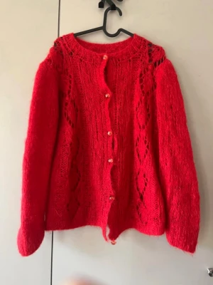Röd stickad kofta med knappar - Så fin röd stickad kofta med hålmönster. Förmodligen handstickad, köpt från Beyond Retro