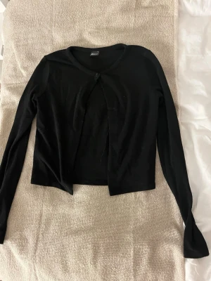 2 koftor från Gina Tricot, svart & beige - Säljer två stilrena koftor från Gina Tricot i storlek S. Ena är svart och den andra beige, båda med lång ärm och en knapp framtill. Perfekta att slänga över en topp eller klänning för en enkel men snygg look.