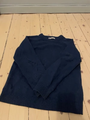 Mörkblå stickad tröja i ullmix - Mysig mörkblå stickad tröja från Cubus i ullblandning. Tröjan har rund hals, ribbade muddar och lång ärm. Perfekt för kyliga dagar och enkel att matcha med jeans.
