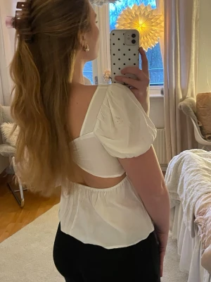 Vit blus med öppen rygg och puffärm - Supersöt vit blus med puffärmar och öppen rygg. Några små fläckar 