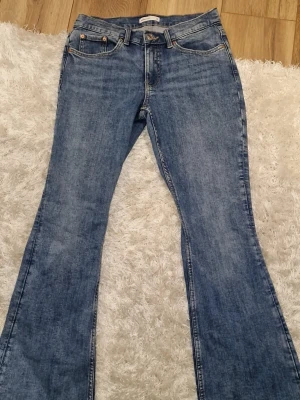 Nya bootcut jeans Gina tricot - Säljer ett par klassiska blå bootcut jeans från Gina tricot i storlek 38. Jeansen har 4 fickor, bälteshällor och snygga kontrastsömmar. DE ÄR NYA