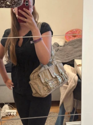 Beige väska - Axelväska som har mycket utrymme med två stora fack och mindre fack i dom. Dessutom finns förvaring utanpå väskan, köpt second hand. Y2K stil. Använd enbart två gånger. Rymlig och dragkedjor fungerar. Skriv om du har frågor!