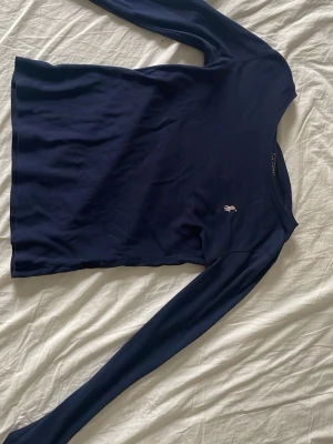 Marinblå långärmad topp Polo Ralph Lauren - Säljer en marinblå långärmad topp från Polo Ralph Lauren. Toppen har en klassisk passform och är prydd med den ikoniska broderade loggan i vitt på bröstet. Tillverkad i mjuk bomull som känns skön mot huden. Perfekt till jeans eller kjol!