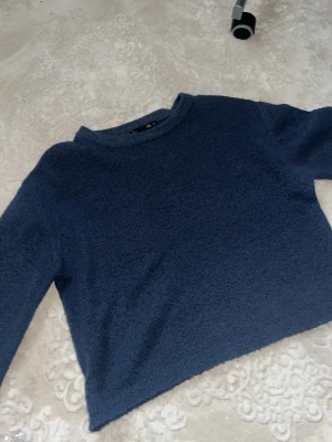 Mörkblå stickad tröja - Mysig mörkblå croppad stickad tröja . Tröjan har en enkel design med rund halsringning och långa ärmar. Perfekt för lager på lager under höst och vinter. Passar dig som gillar en avslappnad men ändå stilren look.
