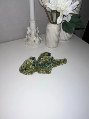Olivgrön bäbisdrake med mörkgröna detaljer🐲 - Denna urgulliga bäbisdrake vill hitta sitt nya hem🐉🐲Den har hårda gröna ögon💚 Den är ungefär likas stor som min handflata🐉 så cirka 15cm långa🐲 Vikrad med massa kärlek, med mjukt garn från Rusta💚💚