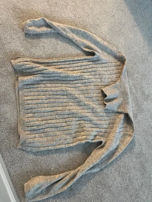 Grå ribbad polotröja Chantelle Ferrand - Säljer en grå ribbad polotröja från Chantelle Ferrand. Tröjan har lång ärm, hög polokrage och är tillverkad i mjukt stickat material. Perfekt för kyliga dagar och enkel att matcha med jeans eller kjol.