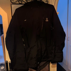 Haglöfs GORE-TEX jacka - Svart vind och regnjacka från Haglöfs i dammodell, storlek XS. Jackan har huva, flera praktiska fickor med dragkedja, ventilation kedja under ärmarna och snyggt Haglöfs-tryck på bröstet. Knappt använd, ny pris runt 3000🩷