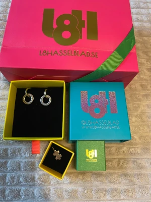 Smycken från L8 Hasselblad  - ”Alla andra är dumma i huvudet” örhängen och en pusselbit berlock