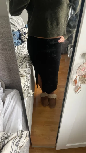 Svart ribbad långkjol med slits - Säljer en svart, ribbad långkjol med snygg slits på sidan. Kjolen har en tight passform som framhäver siluetten och är gjord i ett mjukt, stretchigt material. Perfekt för dig som gillar minimalistisk stil och vill ha något som är både bekvämt och trendigt.