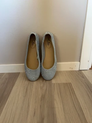 Ljusblå spetsiga ballerinaskor från Clou - Säljer ett par ljusblå ballerinaskor från Clou i storlek 39. Skorna har ett fint spetsmönster över hela ovandelen och rund tå. De är lätta och har platt sula, perfekta för vår och sommar. Superfina detaljer som ger en romantisk vibe.