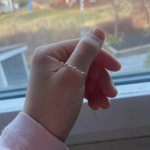 Silverring med kuldetaljer - Säljer en stilren silverring med små kuldetaljer runt om. Perfekt för att bära ensam eller stapla med andra ringar för en unik look. Enkel och elegant design som passar till alla tillfällen.Passar alla kön!