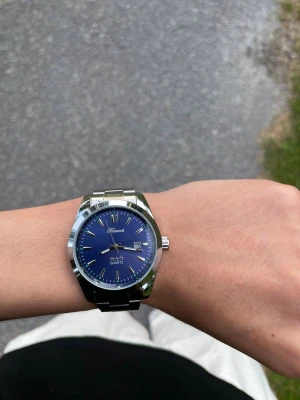 Doventi blå klocka med stållänk - Snygg klocka från Doventi med blå urtavla och datumvisning. Klockan har en rund form och ett stilrent armband i silverfärgat stål. Perfekt accessoar för dig som gillar klassisk och modern stil i ett.